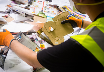 persoon handmatig papier en karton aan het sorteren